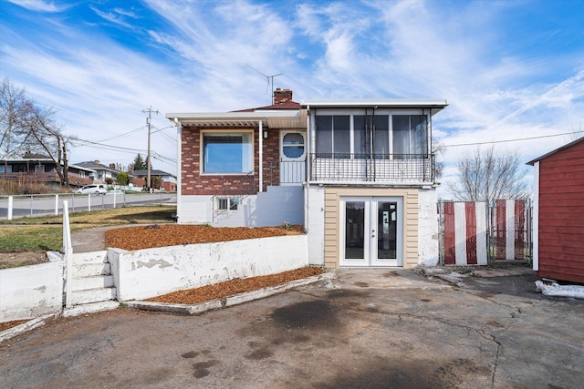 view of front of property featuring a chimney, fence, and french doors