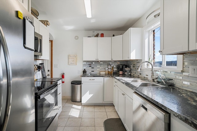 kitchen with light tile patterned floors, stainless steel appliances, decorative backsplash, a sink, and dark countertops