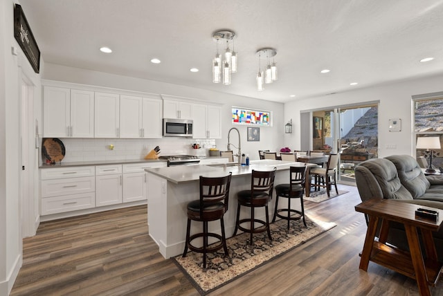 kitchen with range, stainless steel microwave, dark wood finished floors, a sink, and backsplash