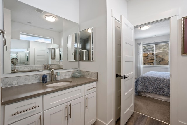 bathroom with wood finished floors, vanity, ensuite bath, and a healthy amount of sunlight
