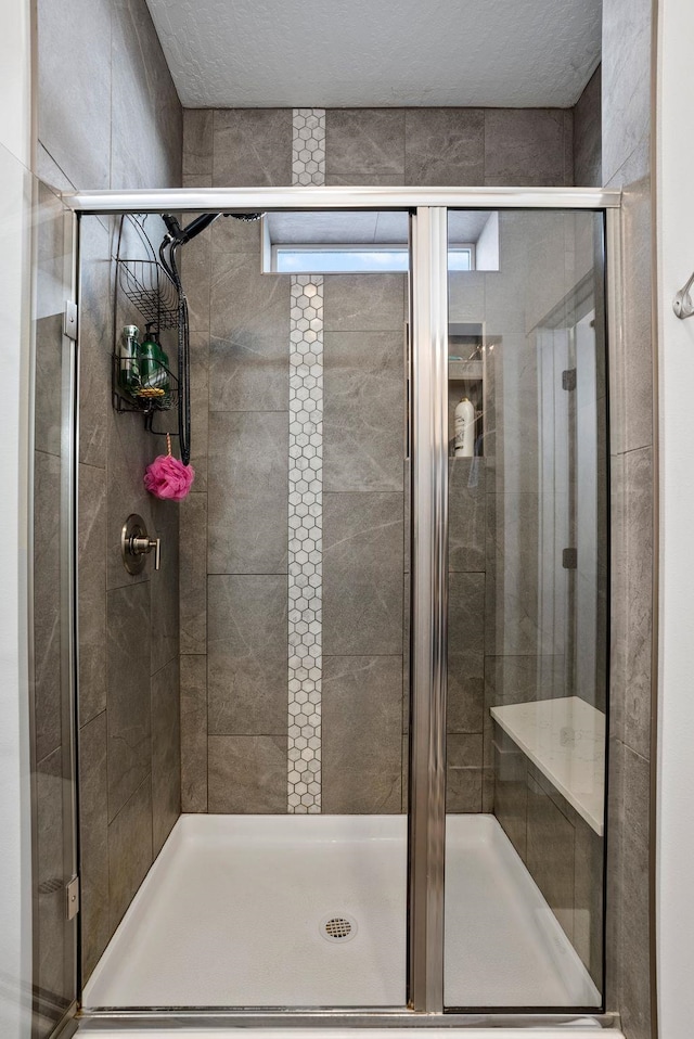 full bath featuring a textured ceiling and a shower stall