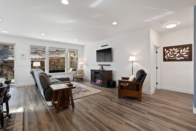 living room featuring baseboards, dark wood-style floors, a glass covered fireplace, and recessed lighting