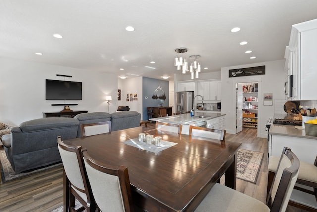 dining area with wood finished floors, an inviting chandelier, and recessed lighting