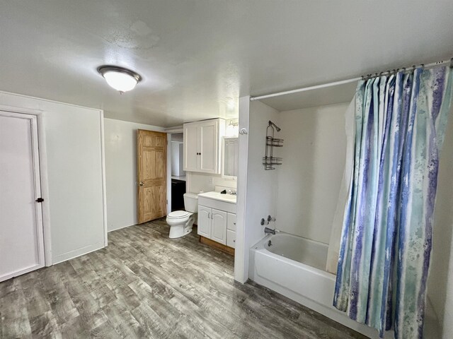 bathroom featuring toilet, wood finished floors, vanity, and shower / bathtub combination with curtain