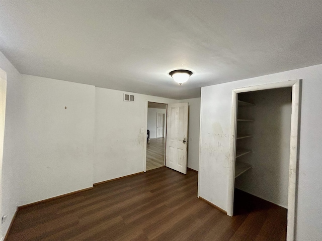 unfurnished bedroom with dark wood-style floors, baseboards, and visible vents