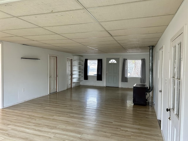 interior space featuring light wood-style flooring, baseboards, and a wood stove