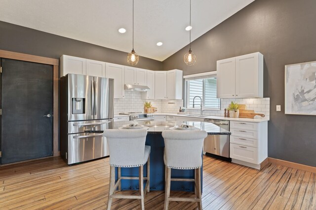 4720 S Wildwood Ln, Spokane, WA 99206 - kitchen featuring white cabinets, under cabinet range hood, a sink, and stainless steel appliances