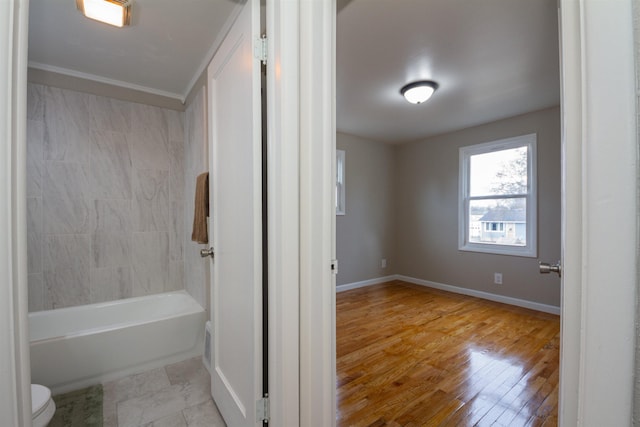 full bath with wood finished floors, toilet, shower / bathing tub combination, baseboards, and crown molding