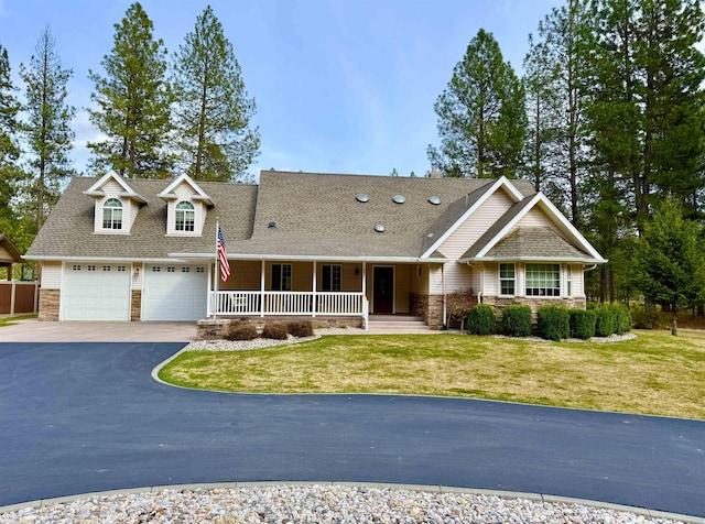 view of front of property with driveway, a front yard, stone siding, a shingled roof, and a porch