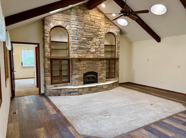 unfurnished living room featuring a ceiling fan, beamed ceiling, a fireplace, and wood finished floors