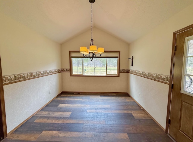 unfurnished dining area with dark wood-style flooring, lofted ceiling, and a chandelier