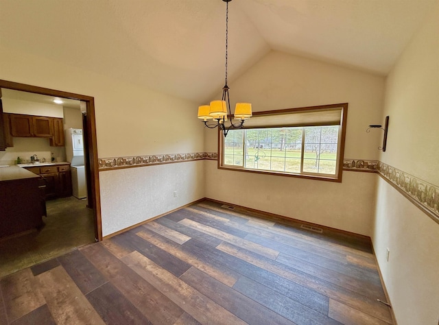 unfurnished dining area with dark wood-type flooring, a sink, vaulted ceiling, and a notable chandelier
