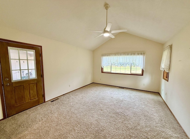 empty room featuring lofted ceiling, visible vents, carpet, and a ceiling fan