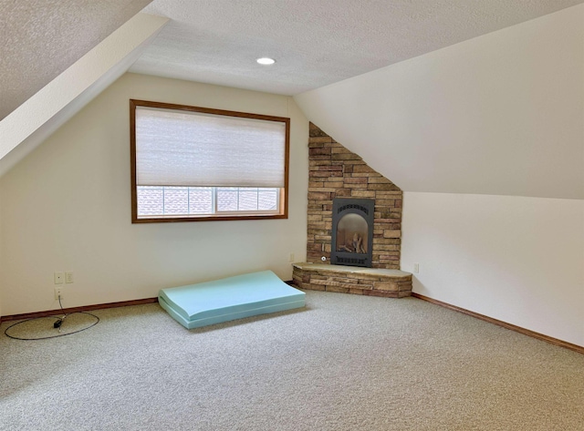 additional living space featuring carpet flooring, baseboards, vaulted ceiling, and a textured ceiling