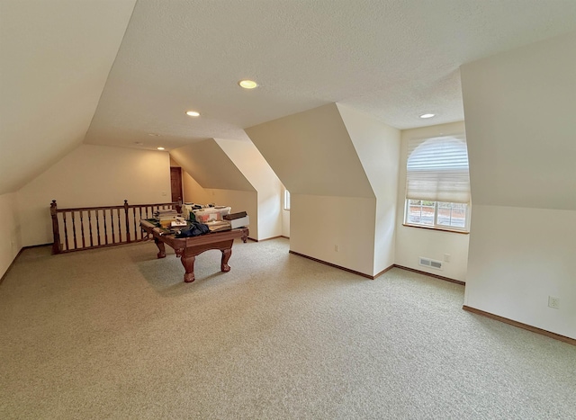 playroom with vaulted ceiling, light colored carpet, baseboards, a textured ceiling, and visible vents