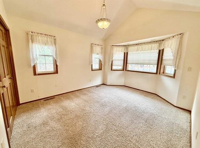 carpeted spare room featuring baseboards, visible vents, and lofted ceiling