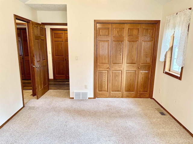 unfurnished bedroom with baseboards, carpet flooring, visible vents, and a closet