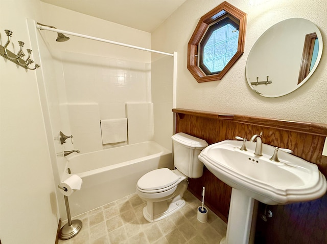 full bath with bathtub / shower combination, toilet, and a textured wall
