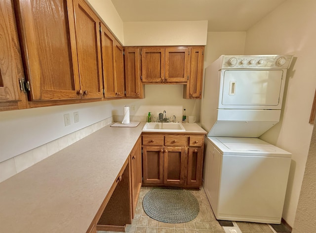 laundry area featuring a sink, stacked washer and clothes dryer, and cabinet space