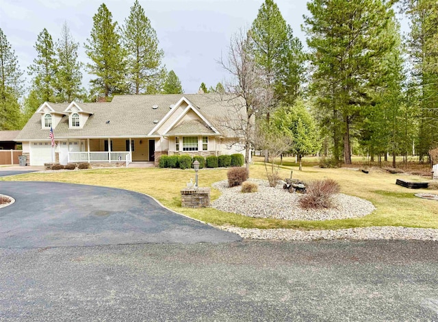 view of front of home with a front yard, a porch, driveway, and a garage