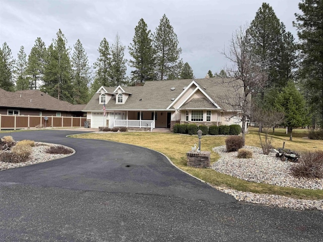 view of front of home with aphalt driveway, fence, an attached garage, a front yard, and a porch