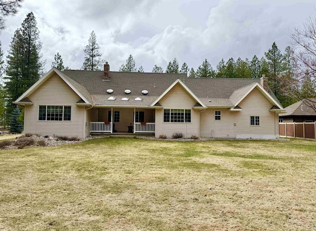 back of house with a chimney, a porch, and a yard