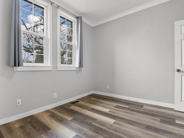 unfurnished room featuring baseboards, visible vents, ornamental molding, and wood finished floors
