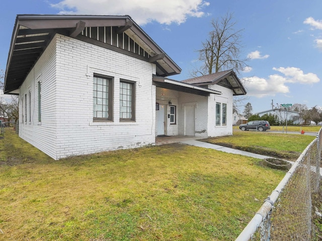 view of front facade with brick siding, fence, and a front lawn