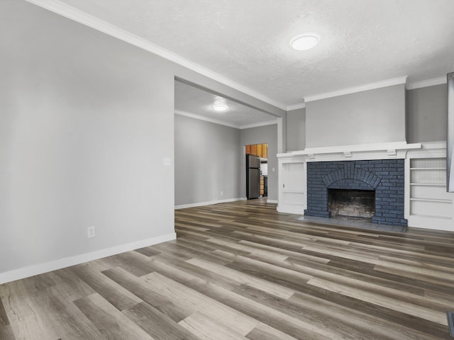 unfurnished living room with baseboards, wood finished floors, ornamental molding, and a textured ceiling