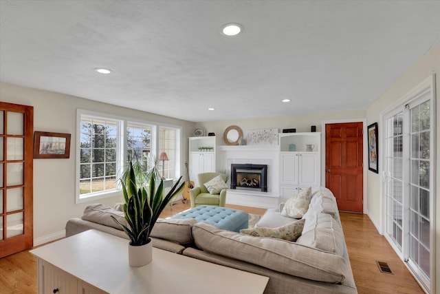 6814 S Jackson Ridge Ln, Greenacres, WA 99016 - living room featuring a fireplace with raised hearth, light wood-style flooring, recessed lighting, and baseboards