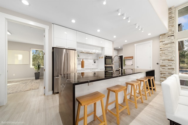 27809 N Bruce Rd, Chattaroy, WA 99003 - kitchen featuring a breakfast bar, decorative backsplash, dark countertops, modern cabinets, and appliances with stainless steel finishes