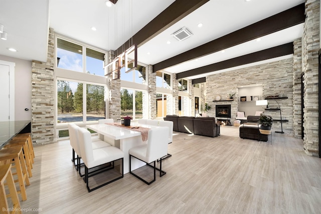27809 N Bruce Rd, Chattaroy, WA 99003 - dining area with beam ceiling, a stone fireplace, light wood-style flooring, visible vents, and a towering ceiling
