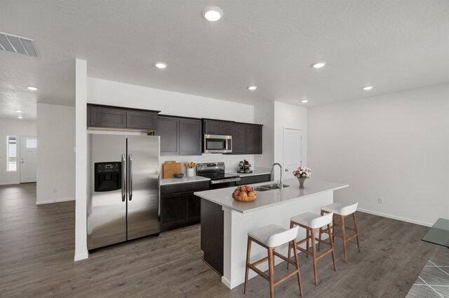 805 E 5th St, Deer Park, WA 99006 - kitchen featuring dark wood-style flooring, a breakfast bar, a kitchen island with sink, stainless steel appliances, and a sink