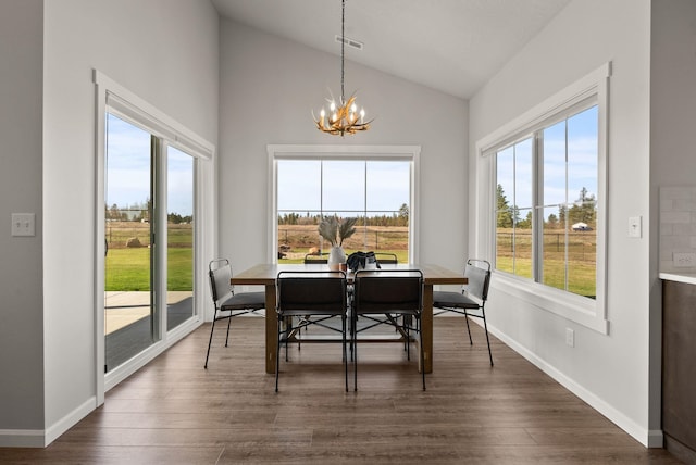 dining room with lofted ceiling, plenty of natural light, an inviting chandelier, and dark wood-style floors