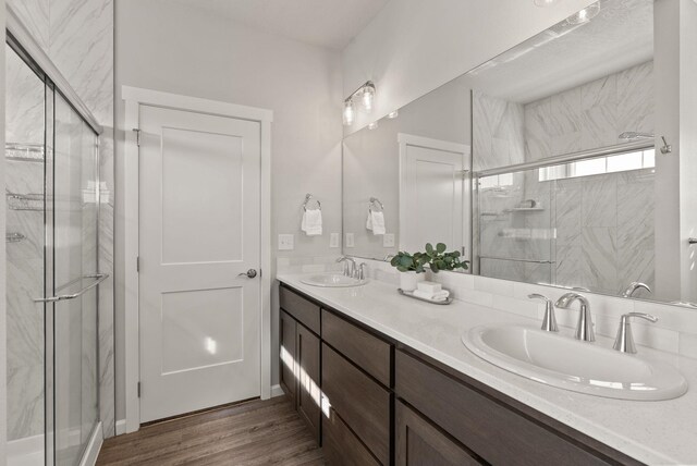 full bath with a walk in closet, a marble finish shower, and wood finished floors