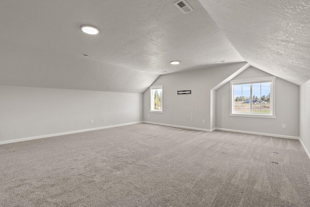 living room featuring a textured ceiling, baseboards, vaulted ceiling, and carpet floors