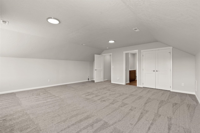 bonus room featuring carpet flooring, baseboards, a textured ceiling, and lofted ceiling