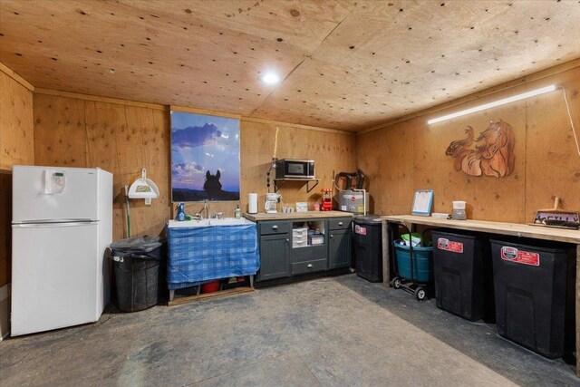 1810 W Paradise Rd, Spokane, WA 99224 - kitchen with concrete flooring, wood walls, light countertops, and freestanding refrigerator