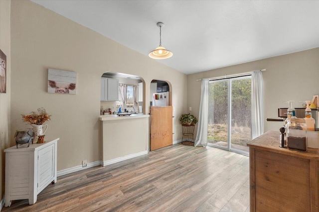 1810 W Paradise Rd, Spokane, WA 99224 - dining room featuring baseboards, light wood-style floors, arched walkways, and vaulted ceiling