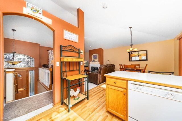 kitchen with light wood-type flooring, vaulted ceiling, a chandelier, white dishwasher, and hanging light fixtures