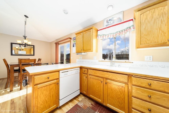 kitchen with a peninsula, light countertops, a sink, dishwasher, and lofted ceiling