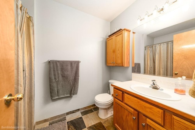 bathroom featuring toilet, baseboards, and vanity
