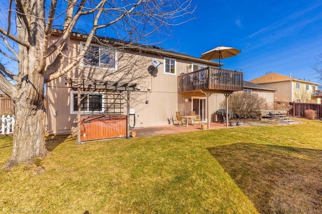 rear view of property featuring a yard, a patio, a hot tub, and fence