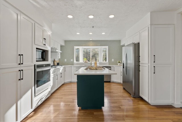 14505 W Coulee Hite Rd, Spokane, WA 99224 - kitchen featuring a center island, light countertops, light wood-style flooring, and stainless steel appliances