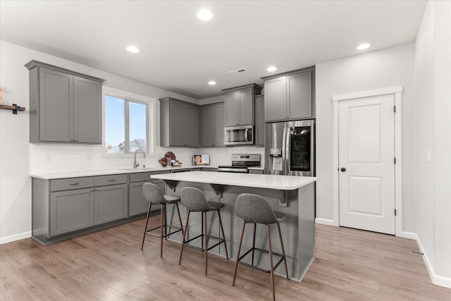 9018 W 72nd Ave, Cheney, WA 99004 - kitchen featuring appliances with stainless steel finishes, gray cabinetry, a breakfast bar area, backsplash, and recessed lighting