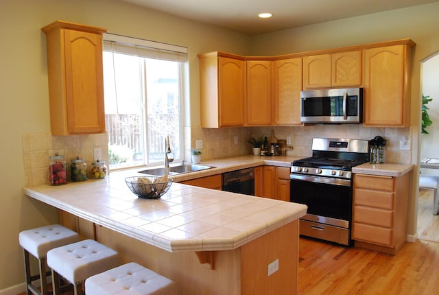 612 N Madson Ct, Liberty Lake, WA 99019 - kitchen with light brown cabinets, a sink, stainless steel appliances, and a peninsula