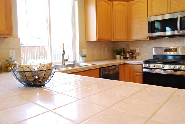 612 N Madson Ct, Liberty Lake, WA 99019 - kitchen featuring a sink, light brown cabinets, tile countertops, stainless steel appliances, and decorative backsplash