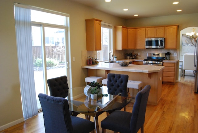 612 N Madson Ct, Liberty Lake, WA 99019 - kitchen with tile counters, tasteful backsplash, stainless steel appliances, light wood-style flooring, and a peninsula