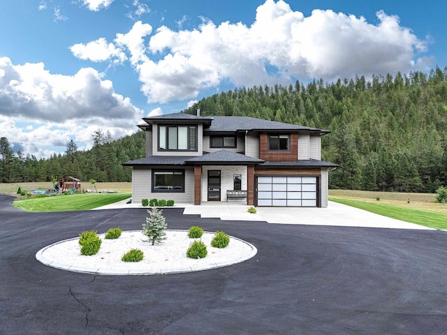 16215 W Coulee Hite Rd, Spokane, WA 99224 - view of front facade featuring a view of trees, a garage, asphalt driveway, and a playground