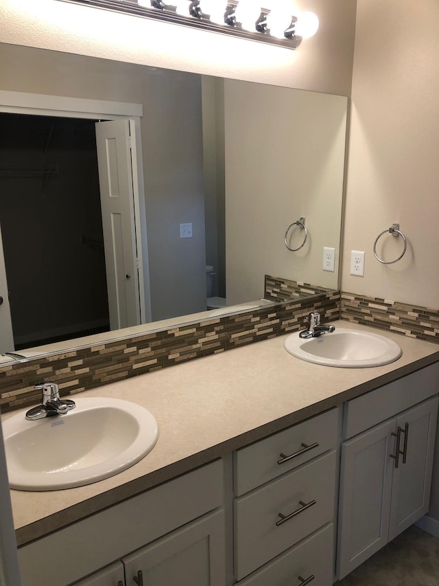 full bath with double vanity, decorative backsplash, and a sink